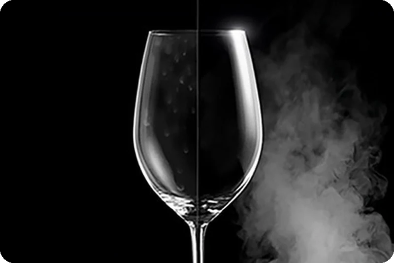 A wine glass with water spots on one side, and clear and pristine on the other after steam washing.