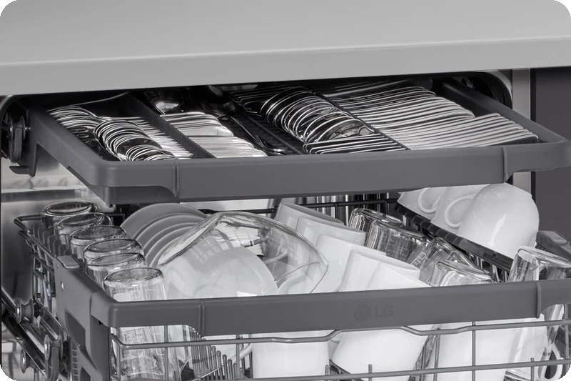 Spatulas, spoons, forks and knives arranged in the dishwasher's third rack.