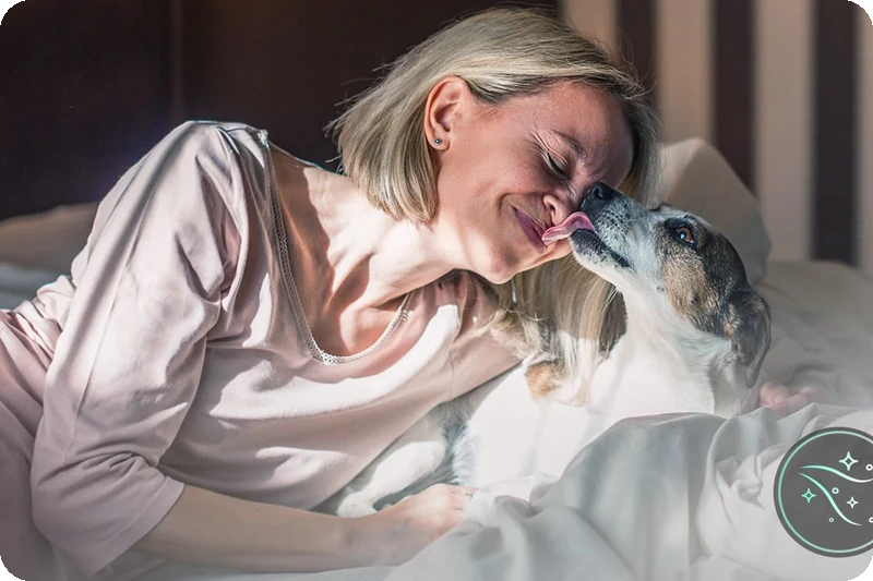 Woman and dog relaxing on a bed after using the LG Pet Care wash cycle.