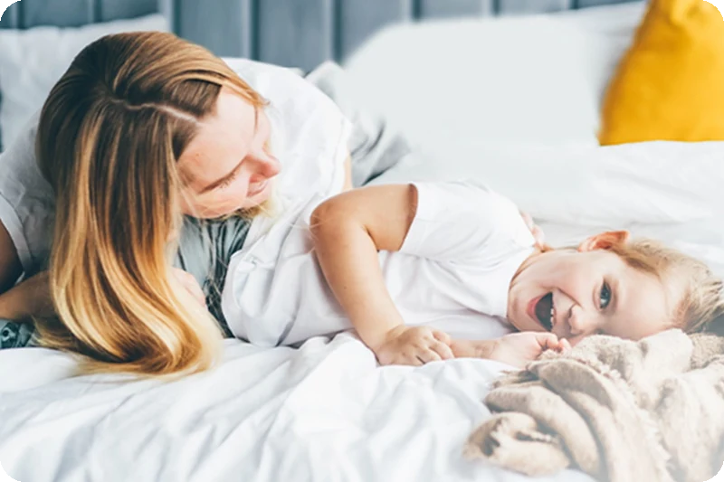 A parent and child relaxing on clean bedding after an LG Steam Allergy Care wash.