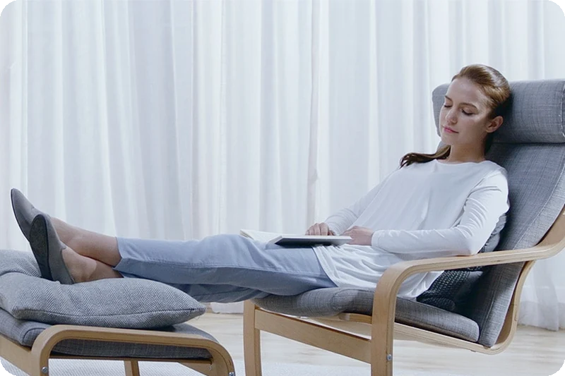 Woman relaxing while the LG dryer operates in Eco Hybrid energy mode.