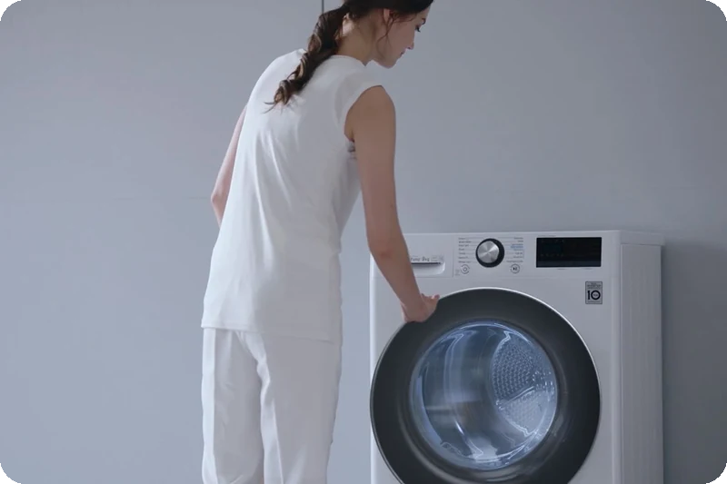 Woman caring for clothes beside the LG heat-pump dryer.